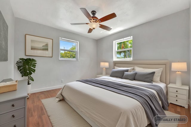 bedroom featuring multiple windows, ceiling fan, baseboards, and wood finished floors