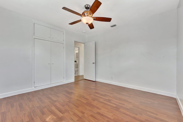 unfurnished bedroom featuring wood finished floors, baseboards, and a closet
