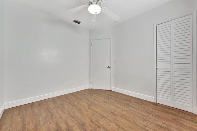 unfurnished bedroom featuring visible vents, ceiling fan, baseboards, wood finished floors, and a closet