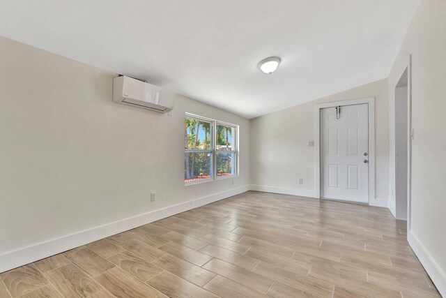 empty room with wood finish floors, baseboards, and a wall unit AC