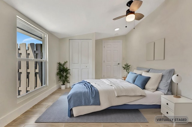 bedroom with a ceiling fan, a closet, baseboards, wood tiled floor, and vaulted ceiling