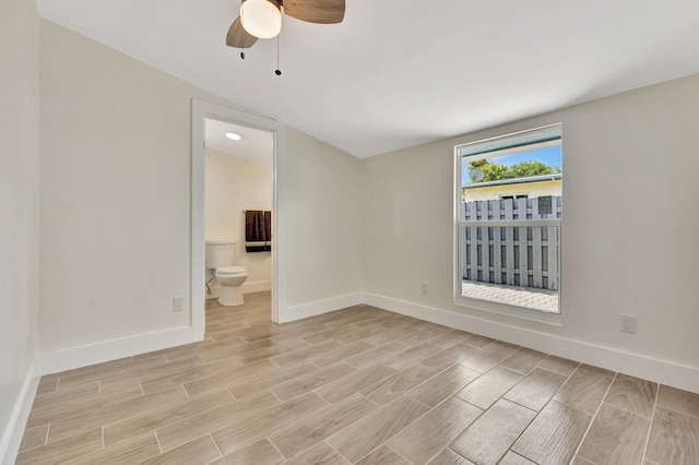 empty room with baseboards, a ceiling fan, and wood tiled floor