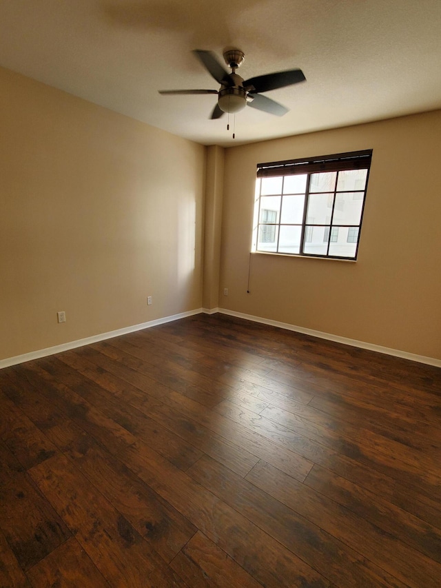 unfurnished room with ceiling fan, baseboards, and dark wood-style flooring