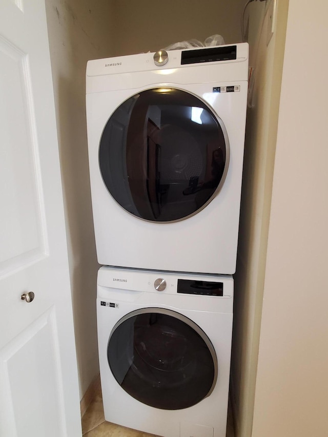 laundry area featuring light tile patterned floors, laundry area, and stacked washer / dryer