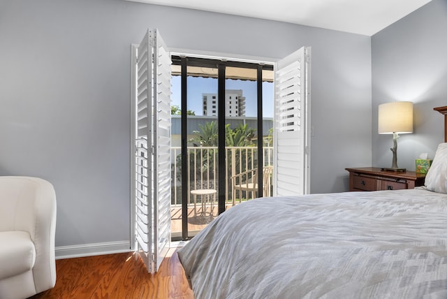 bedroom featuring baseboards, wood finished floors, and access to outside