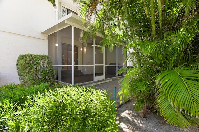 view of side of property with a balcony, a sunroom, and stucco siding