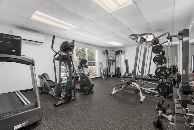 workout area featuring a drop ceiling and an AC wall unit