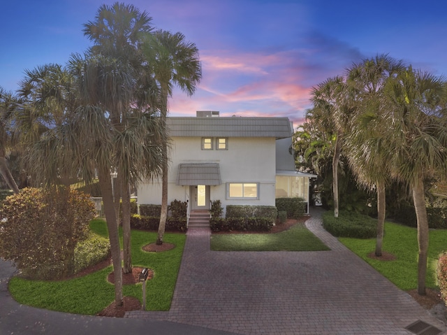 view of front of home with a front yard, decorative driveway, and stucco siding