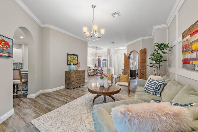 living area featuring wood finished floors, visible vents, arched walkways, crown molding, and a chandelier