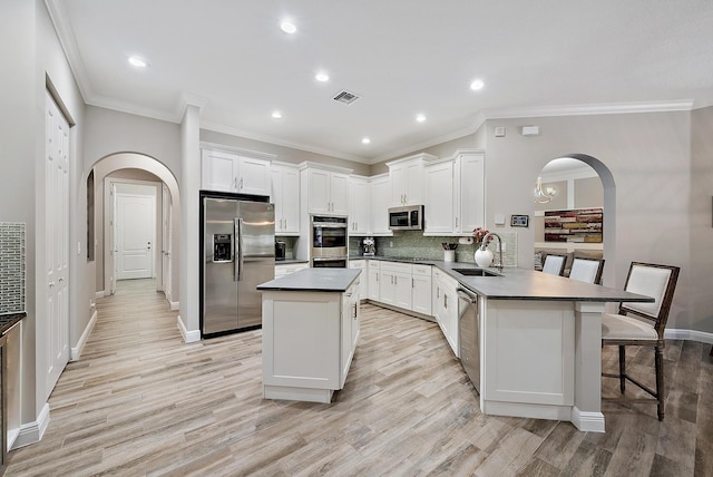 kitchen featuring visible vents, appliances with stainless steel finishes, a peninsula, arched walkways, and a sink