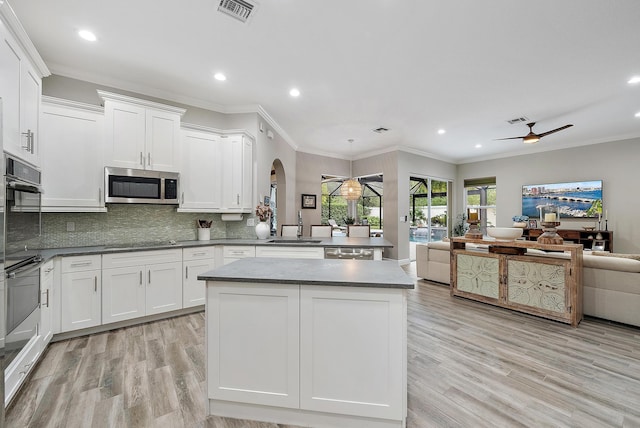 kitchen with visible vents, open floor plan, arched walkways, white cabinets, and black appliances