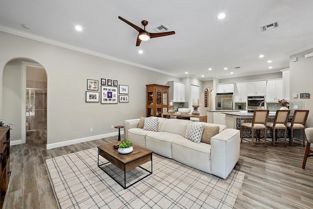 living area featuring arched walkways, visible vents, and light wood-style floors