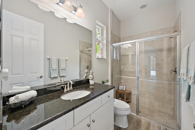 full bathroom featuring vanity, a shower stall, toilet, and wood finished floors