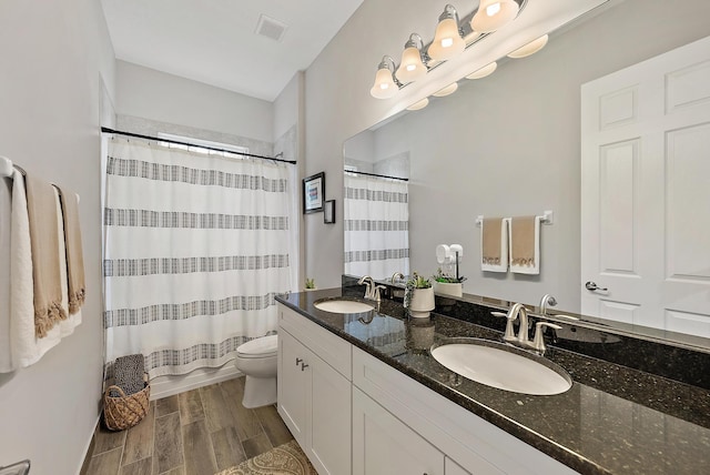 bathroom featuring visible vents, toilet, wood finished floors, and a sink