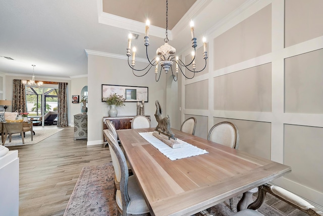 dining space featuring visible vents, crown molding, a tray ceiling, light wood-style floors, and a notable chandelier