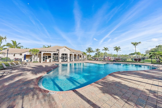 community pool with a patio and fence