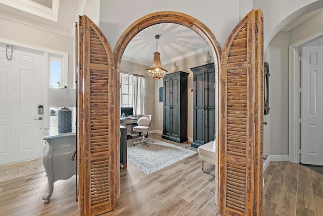 entrance foyer featuring baseboards, arched walkways, ornamental molding, and wood tiled floor