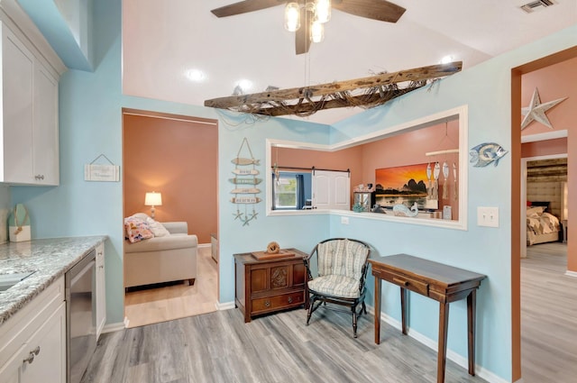 living area with visible vents, light wood-style flooring, baseboards, and ceiling fan