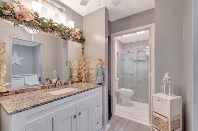 full bath with toilet, a textured ceiling, wood finished floors, a shower stall, and vanity