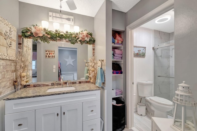 bathroom featuring toilet, a textured ceiling, a shower stall, ceiling fan, and vanity