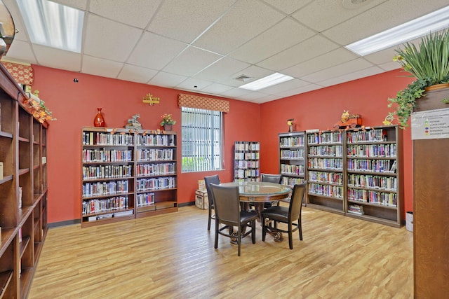 dining space featuring baseboards, wood finished floors, visible vents, and a paneled ceiling