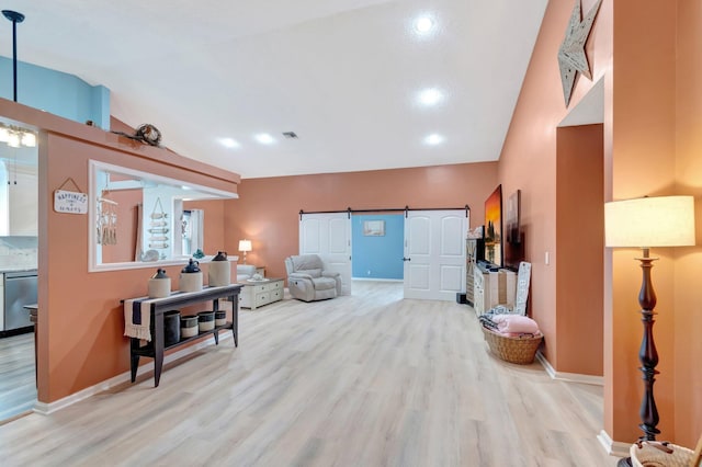 interior space featuring a barn door, light wood-style flooring, and vaulted ceiling