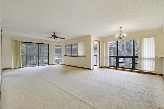 unfurnished living room featuring baseboards, ceiling fan with notable chandelier, a textured ceiling, and carpet