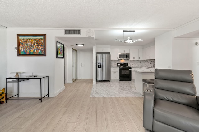 living room featuring baseboards, visible vents, light wood finished floors, and a textured ceiling