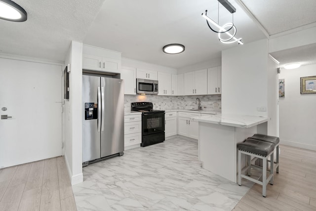 kitchen with backsplash, a peninsula, stainless steel appliances, white cabinetry, and a sink