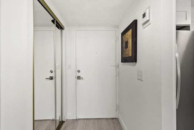 entryway with a textured ceiling and light wood-style flooring