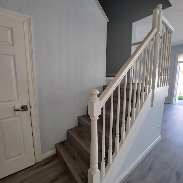 stairs with wood finished floors and a textured wall