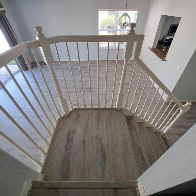 staircase with a notable chandelier and wood finished floors