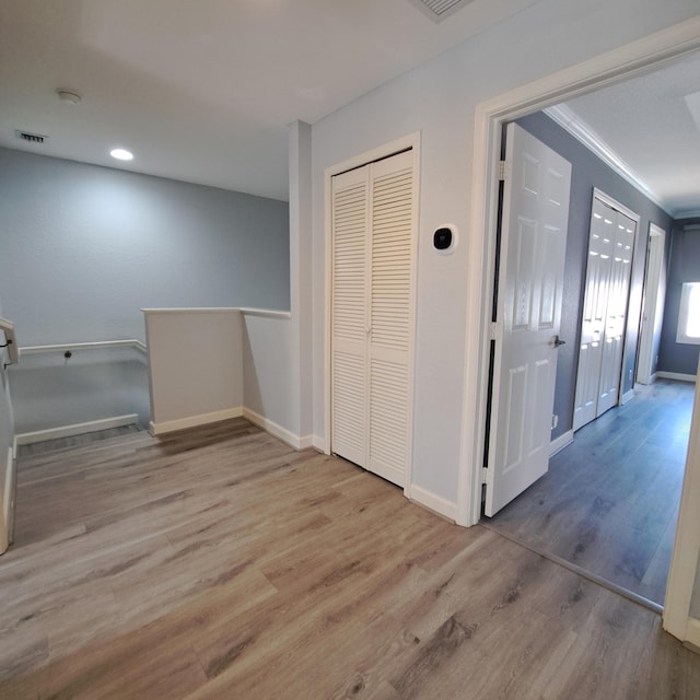 hall featuring wood finished floors, visible vents, and baseboards