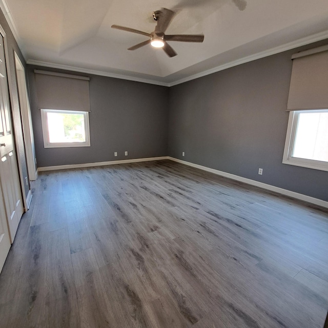 unfurnished bedroom with a raised ceiling, crown molding, baseboards, and wood finished floors