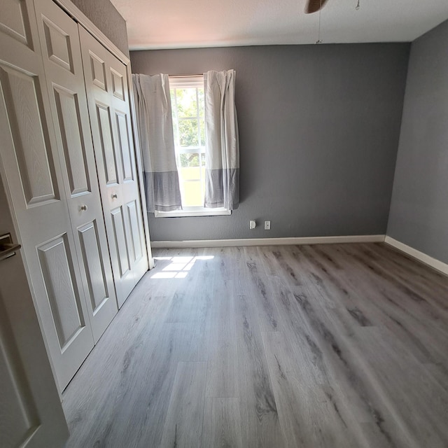 unfurnished bedroom with a closet, baseboards, and wood finished floors