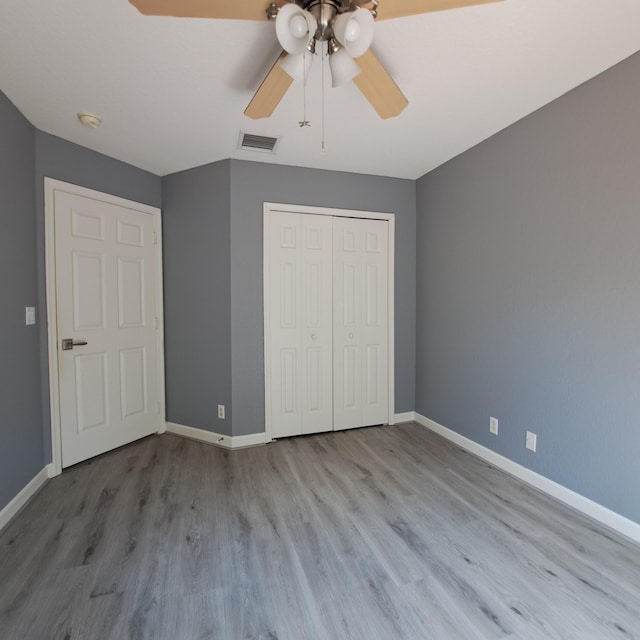 unfurnished bedroom featuring a closet, visible vents, baseboards, and wood finished floors