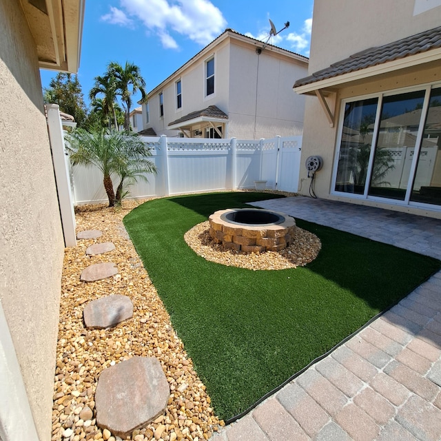 view of yard with a patio area, a fenced backyard, and an outdoor fire pit