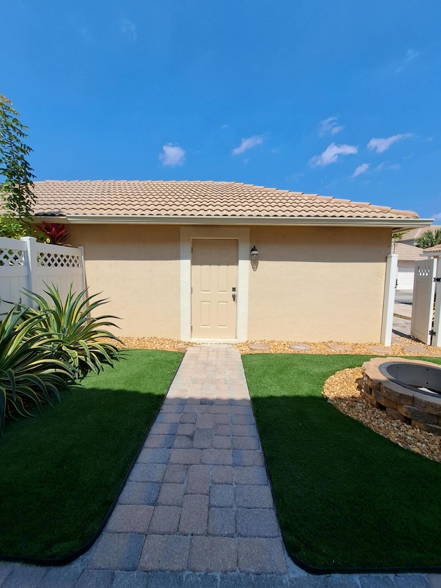 exterior space with stucco siding, a yard, a tile roof, and fence