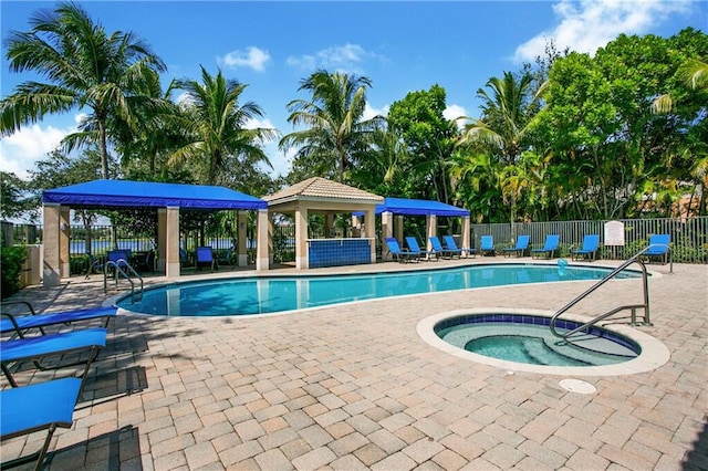 community pool with a gazebo, fence, a hot tub, and a patio