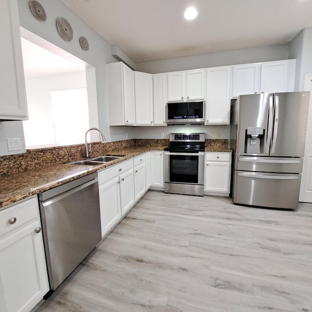 kitchen featuring a sink, appliances with stainless steel finishes, white cabinets, and light wood finished floors