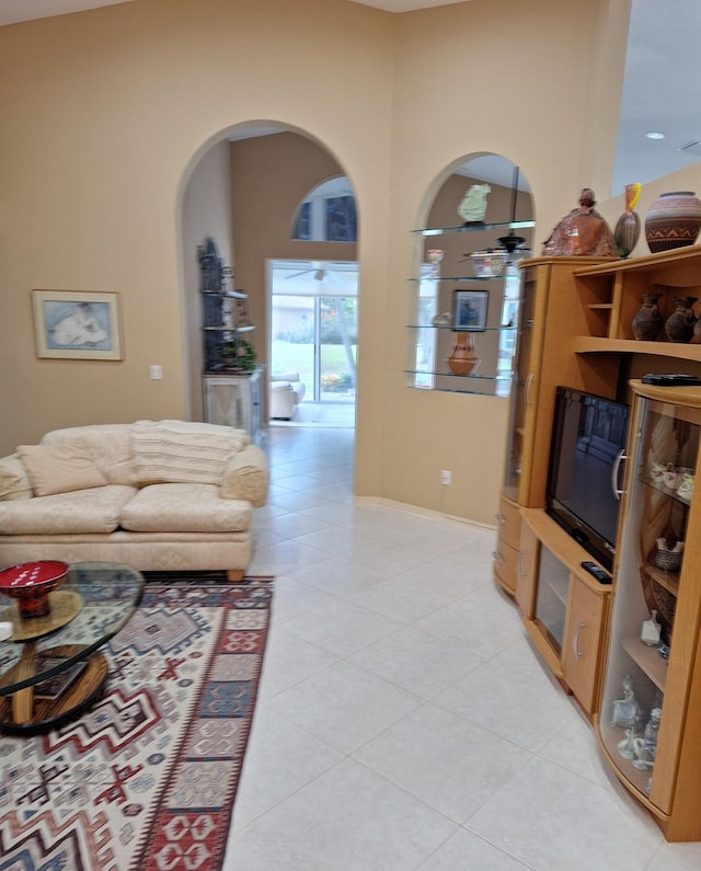 living room featuring light tile patterned floors, baseboards, a high ceiling, and ceiling fan