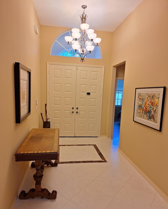 foyer with a chandelier, baseboards, and light tile patterned flooring