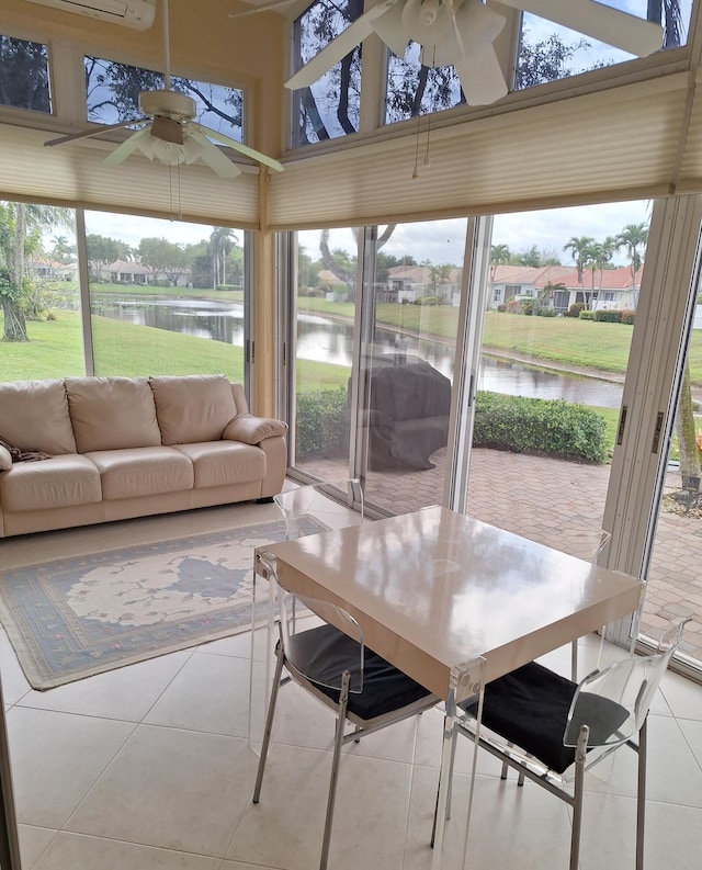 sunroom / solarium with plenty of natural light, a ceiling fan, and a water view