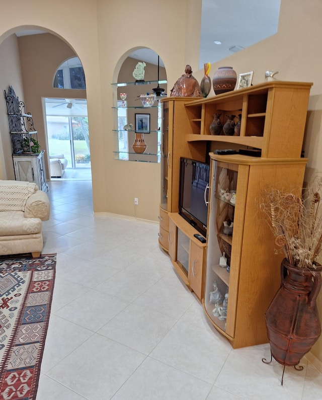 living room with a high ceiling, light tile patterned floors, and ceiling fan