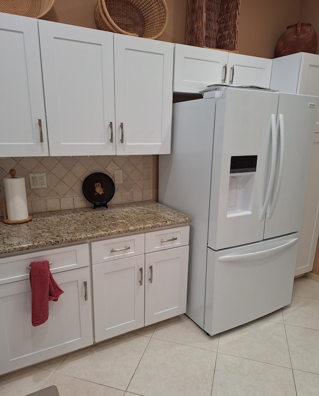 kitchen with light tile patterned flooring, decorative backsplash, white cabinetry, and white fridge with ice dispenser