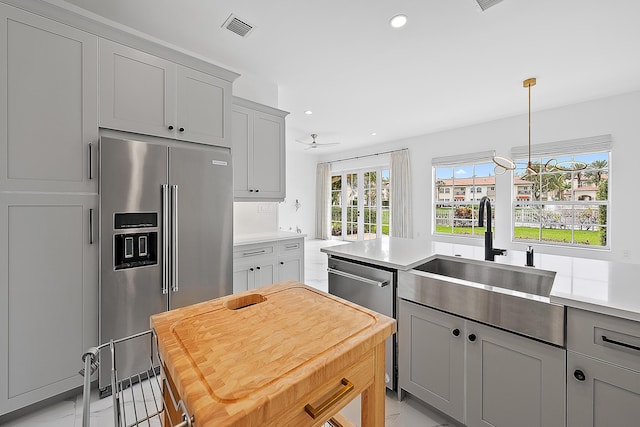 kitchen with a sink, stainless steel appliances, visible vents, and gray cabinetry