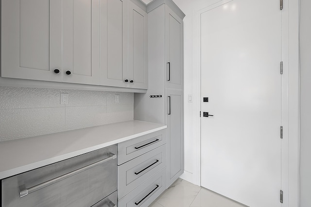 interior space featuring light countertops, tasteful backsplash, marble finish floor, and gray cabinetry