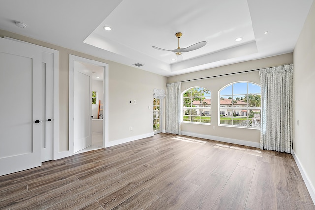 unfurnished room featuring visible vents, a raised ceiling, and wood finished floors