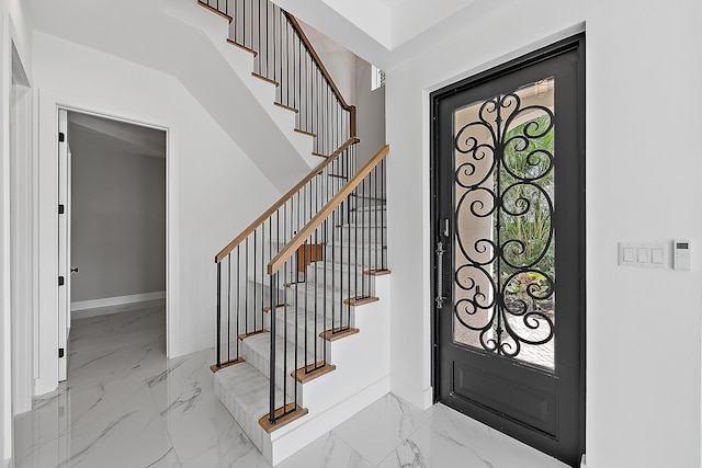 entrance foyer with stairway, marble finish floor, and baseboards