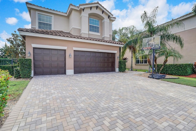 mediterranean / spanish-style house featuring a tiled roof, decorative driveway, an attached garage, and stucco siding